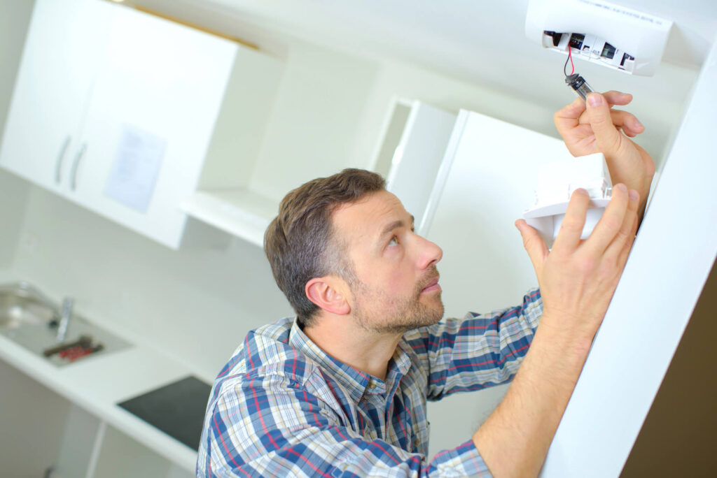 man installing smoke alarm detector in a house
